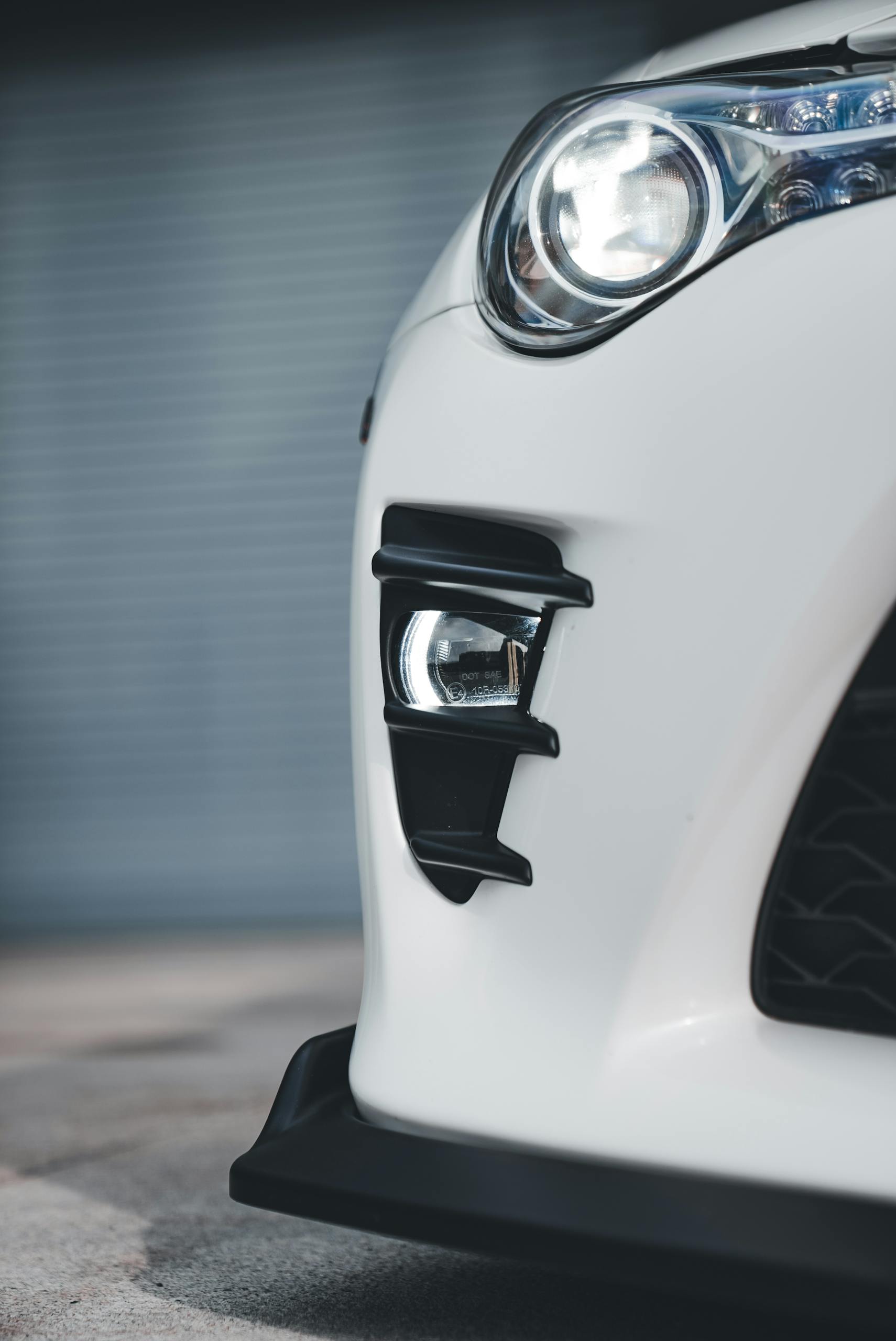Detailed image of a white sports car's front showcasing its sleek headlight design, ideal for automotive themes.